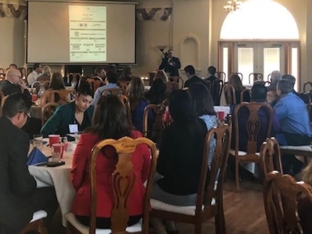 Audience attending lunch and presentation in large dining hall